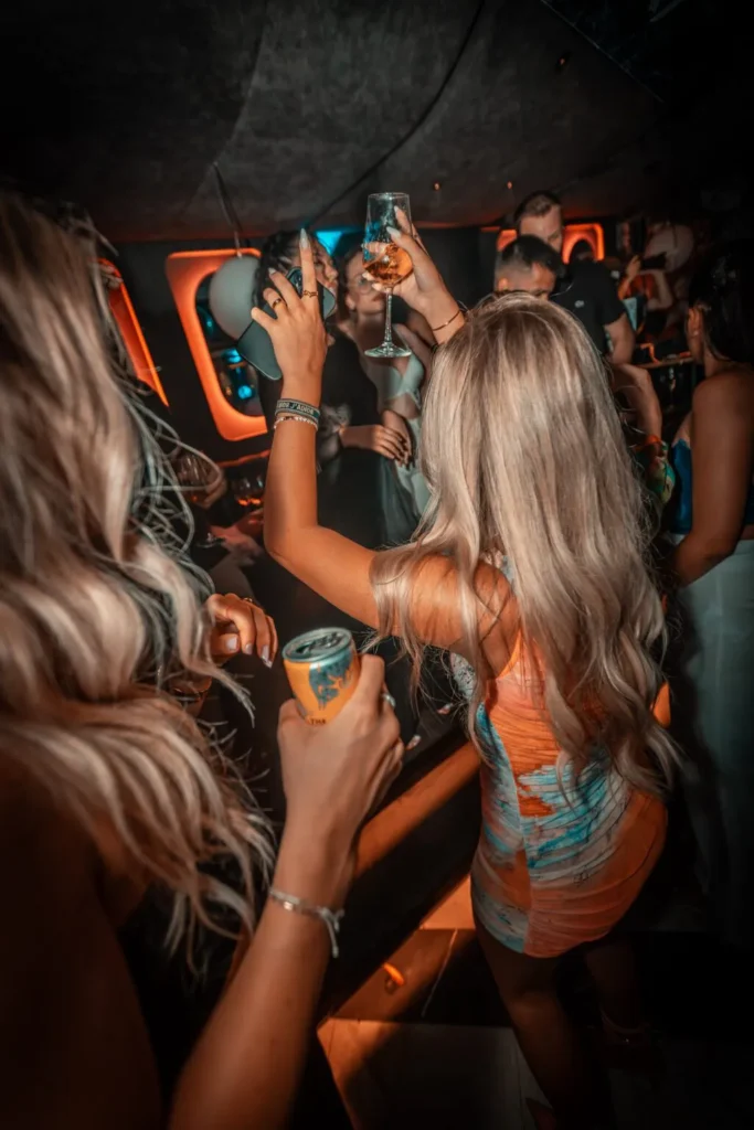 Junge Frauen tanzen mit Drinks in der Hand auf einer Party im Le Jardin Linz bei gedimmtem Licht und Clubatmosphäre.
